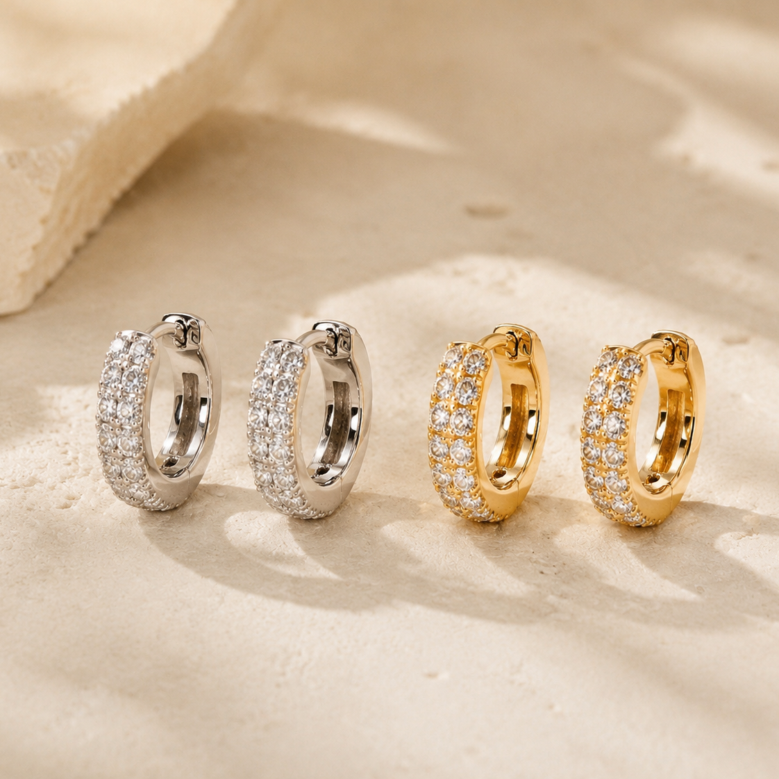 DHARIN Mini Diamond Huggie Earrings - editorial, two pairs silver and gold side by side, limestone surface